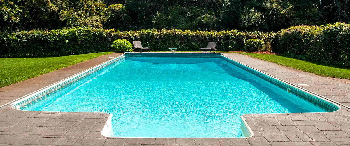 Beautiful backyard with a sparkling in-ground swimming pool surrounded by lush green landscaping.